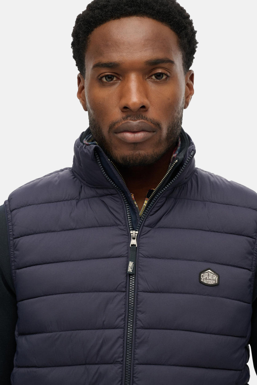 Blauwe mouwloze jas van SUPERDRY, gewatteerd met zichtbare ritssluiting.