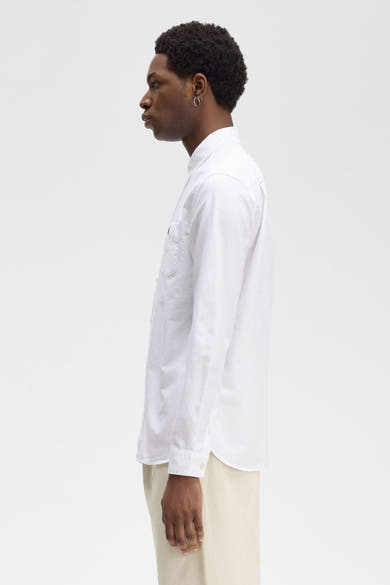 Wit overhemd met lange mouwen van FRED PERRY, zijaanzicht, met borstzak en een beige broek.