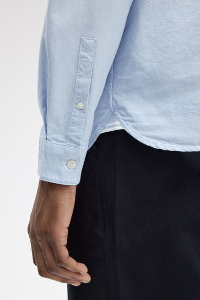 Blauwe blouse met lange mouwen van FRED PERRY, met knoopmanchetten en subtiele textuurdetails.