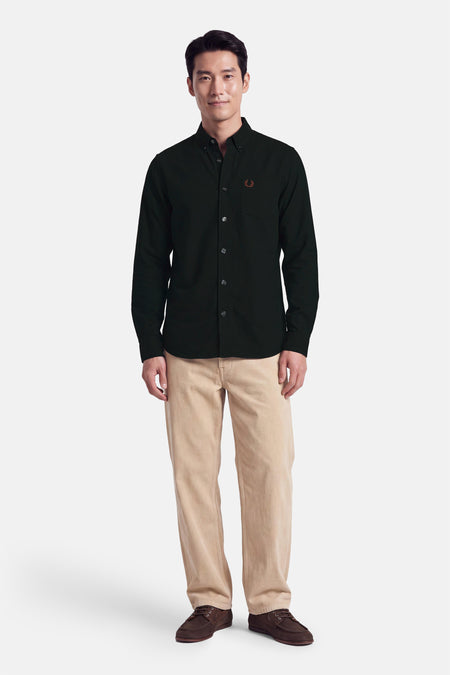 Chemise à manches longues vert foncé FRED PERRY, portée par un mannequin, avec poche poitrine et logo brodé.