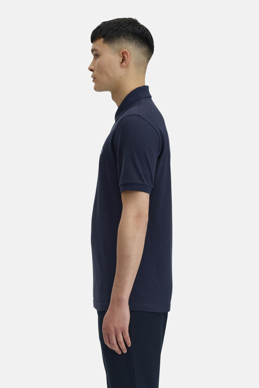 Polo bleu marine de Fred Perry, porté par un homme vu de profil.
