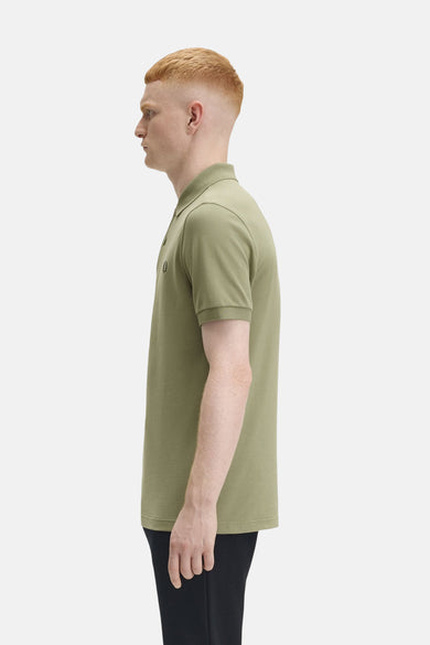 Olijfgroen poloshirt met korte mouwen van FRED PERRY, zijprofiel, gedragen met een zwarte broek.