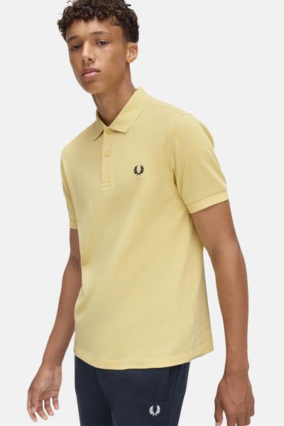 Polo à manches courtes jaune de Fred Perry, avec le logo laurier brodé sur la poitrine.