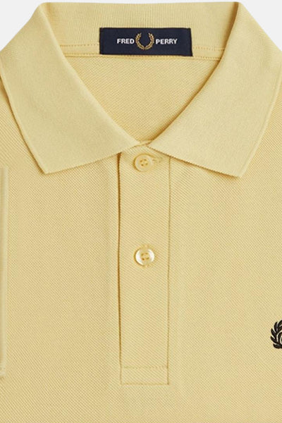 Polo jaune à manches courtes de Fred Perry, avec deux boutons et le logo subtil.
