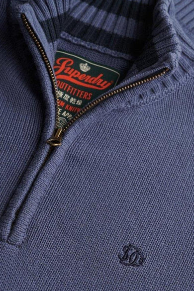 Pull à col roulé bleu par SUPERDRY avec fermeture éclair et étiquette de la marque.