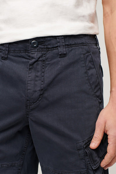 Short bleu de SUPERDRY, avec une texture sergée, porté avec un t-shirt blanc uni.