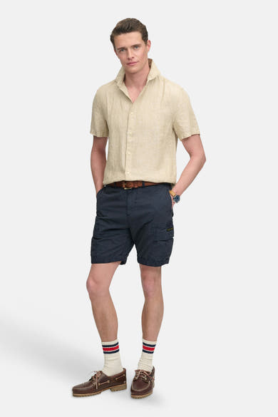 Donkerblauwe korte broek van SUPERDRY, cargostijl met zijzakken en omslag, gedragen met een linnen hemd.