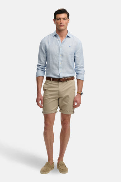 Korte beige, SUPERDRY, gedragen met een lichtblauw overhemd met lange mouwen, een gevlochten riem en loafers.