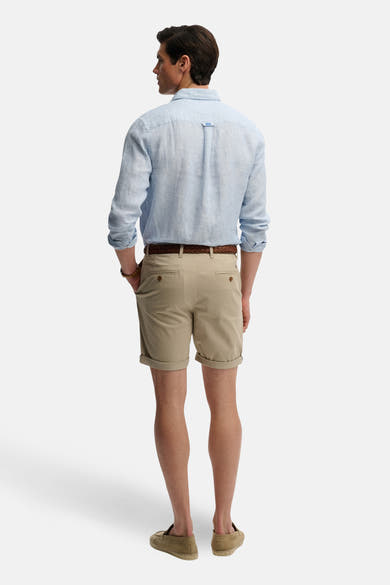 Korte beige short van SUPERDRY, gedragen met een gevlochten riem en een lichtblauw linnen overhemd, van achteren gezien.