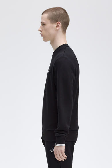 Zwarte rondehals sweatshirt van Fred Perry, met het logo op de voorkant, in profielaanzicht.