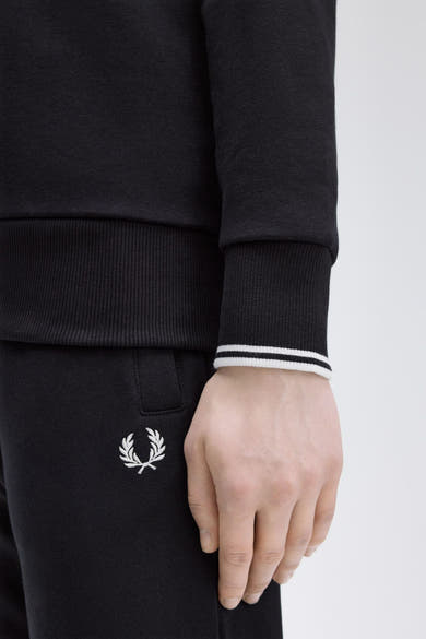 Zwarte Fred Perry sweater, met gestreepte manchetten en geborduurd logo op de bijpassende broek.