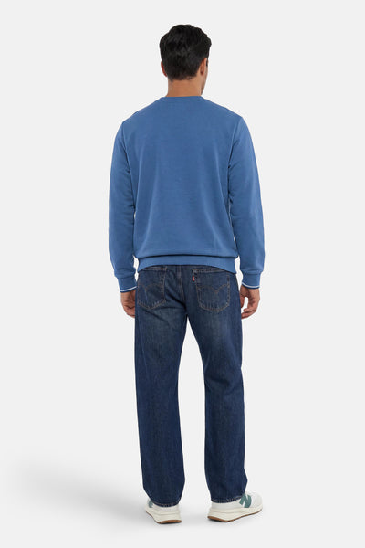 Blauwe sweater met ronde hals van FRED PERRY, van achteren gedragen door een man met een gestreept detail aan de manchetten.