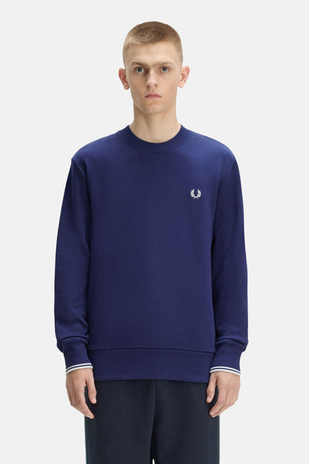 Blauwe rondehals sweatshirt van FRED PERRY met wit lauriertaklogo op de borst, gedragen door een man.