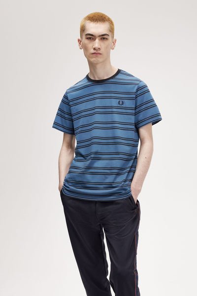 Blauw gestreept T-shirt, van FRED PERRY, gedragen met een marineblauwe joggingbroek.