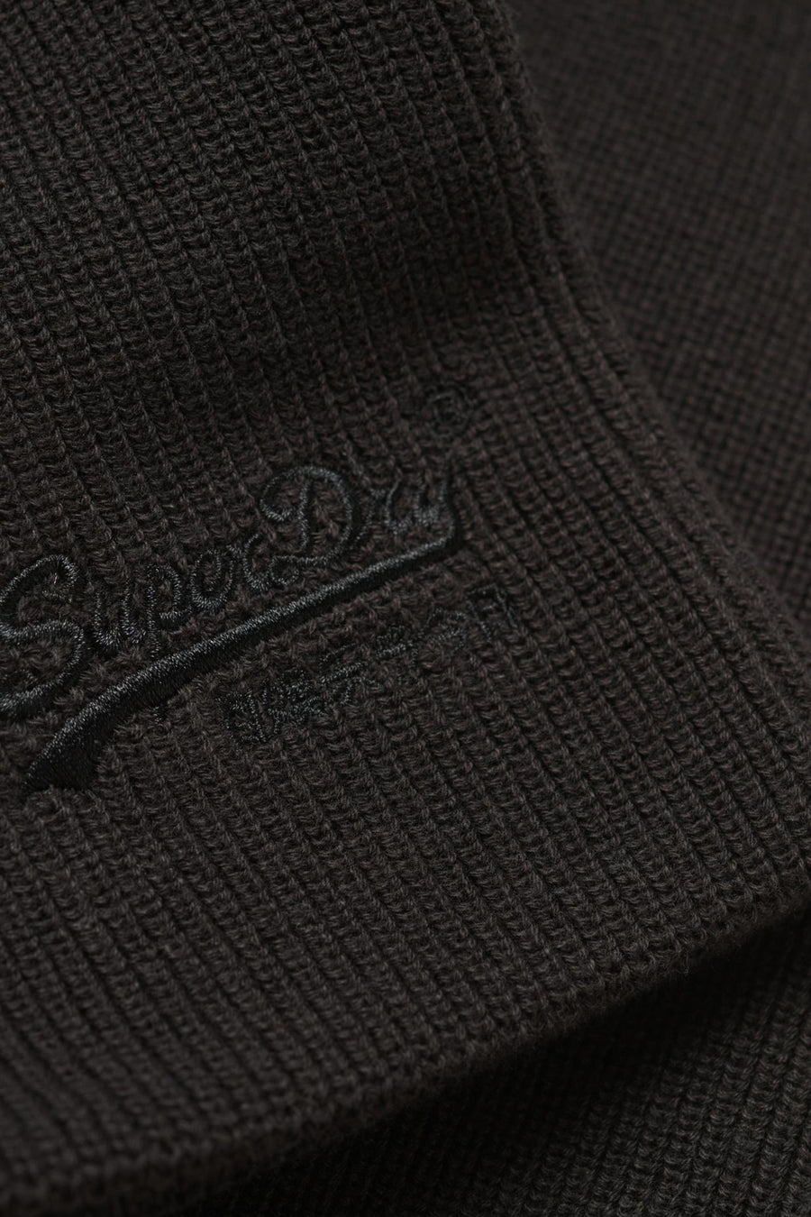 Casquette noire de SUPERDRY, texture tricotée avec logo brodé ton sur ton.

