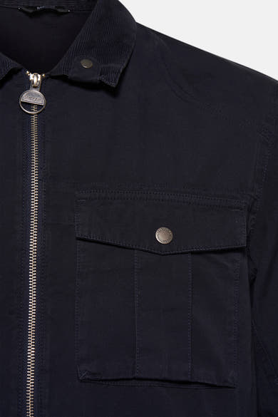 Veste de pluie bleue par BARBOUR, avec fermeture éclair et poche boutonnée sur le devant.