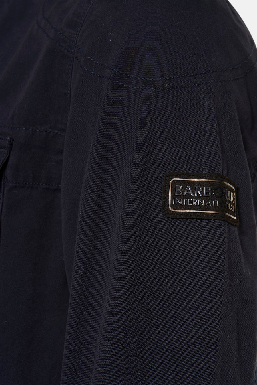 Veste de pluie bleue par BARBOUR, avec patch logo sur la manche et surpiqûres ton sur ton.