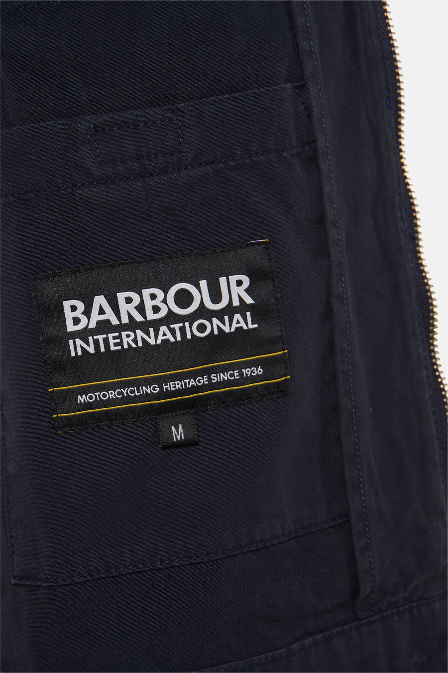 Veste de pluie bleue de BARBOUR International avec étiquette de la marque et indications de taille.