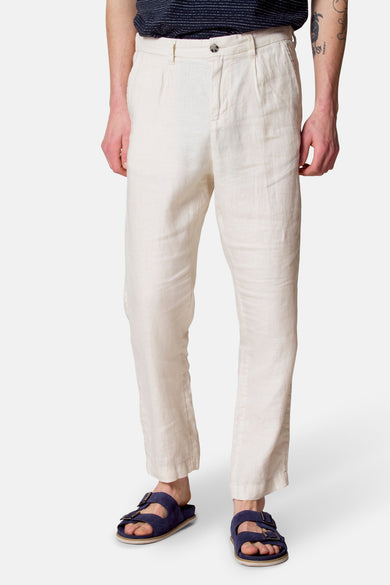 Pantalon de costume beige par Le Fabuleux Marcel de Bruxelles, en lin texturé, porté avec des sandales bleues.
