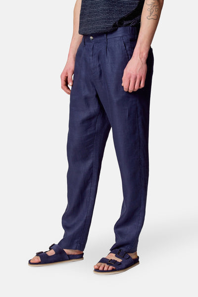 Pantalon de costume bleu par Le Fabuleux Marcel de Bruxelles, avec plis, porté avec des sandales bleues.
