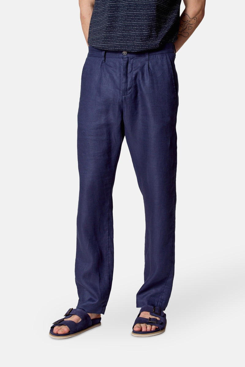 Pantalon de costume bleu de Le Fabuleux Marcel de Bruxelles, en lin, porté avec des sandales assorties.