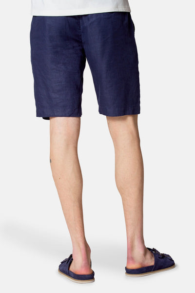 Short bleu de Le Fabuleux Marcel de Bruxelles, en lin, porté avec des sandales bleues.