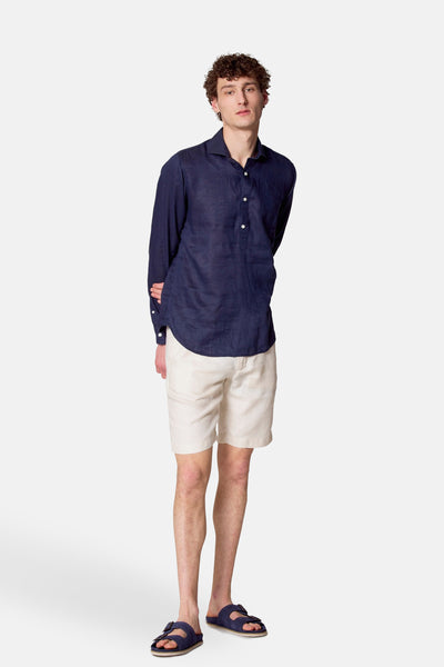 Blauwe lange mouw chemise van Le Fabuleux Marcel van Brussel, gedragen met een beige short en blauwe sandalen.