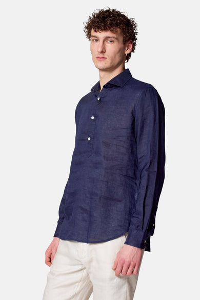 Blauwe linnen chemise met lange mouwen van Le Fabuleux Marcel van Brussel, gedragen met een heldere broek.