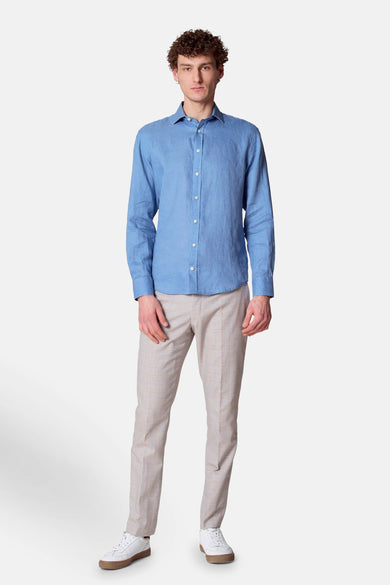 Blauwe blouse met lange mouwen van Le Fabuleux Marcel de Bruxelles, gedragen met een geruite broek en witte sneakers.