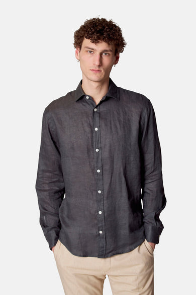 Chemise à manches longues vert foncé de Le Fabuleux Marcel de Bruxelles, portée avec un pantalon beige clair, manches retroussées.