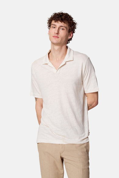 Beige T-shirt met korte mouwen van Le Fabuleux Marcel de Bruxelles, van linnen, gedragen door een man met krullend haar.