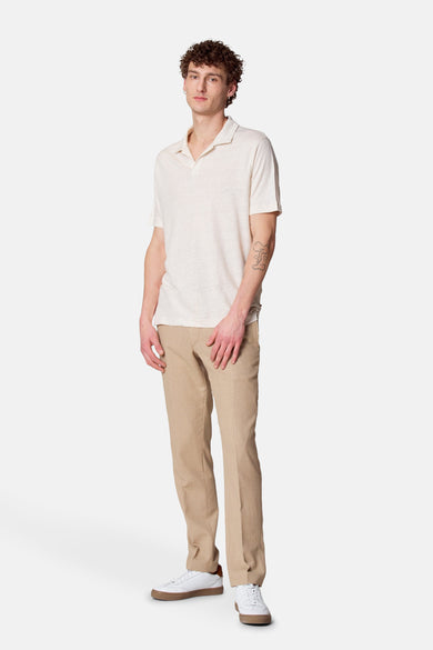 Beige poloshirt met korte mouwen van Le Fabuleux Marcel de Bruxelles, gedragen met een witte broek en witte sneakers.