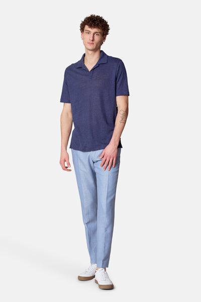 Blauw poloshirt met korte mouwen van Le Fabuleux Marcel uit Brussel, gedragen met een lichtblauwe broek en witte schoenen.