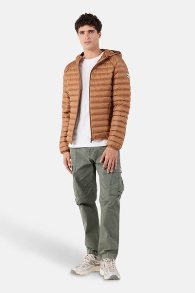 Veste de pluie marron de JOTT, portée sur un t-shirt blanc, avec un pantalon cargo vert olive et des baskets.