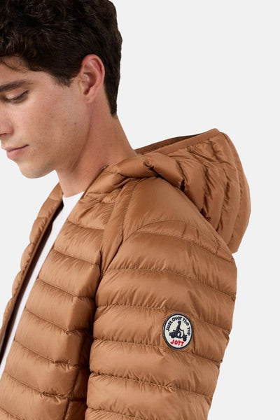 Veste de pluie marron de JOTT, matelassée avec capuche, portée sur un t-shirt blanc.