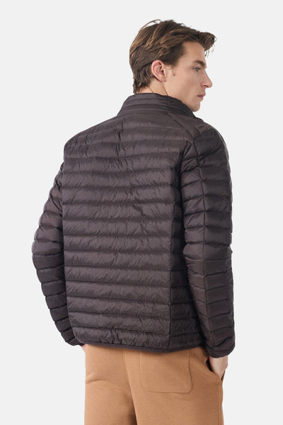 Veste de pluie marron, par JOTT, avec motif matelassé et détails de style subtils, portée avec un pantalon marron clair.
