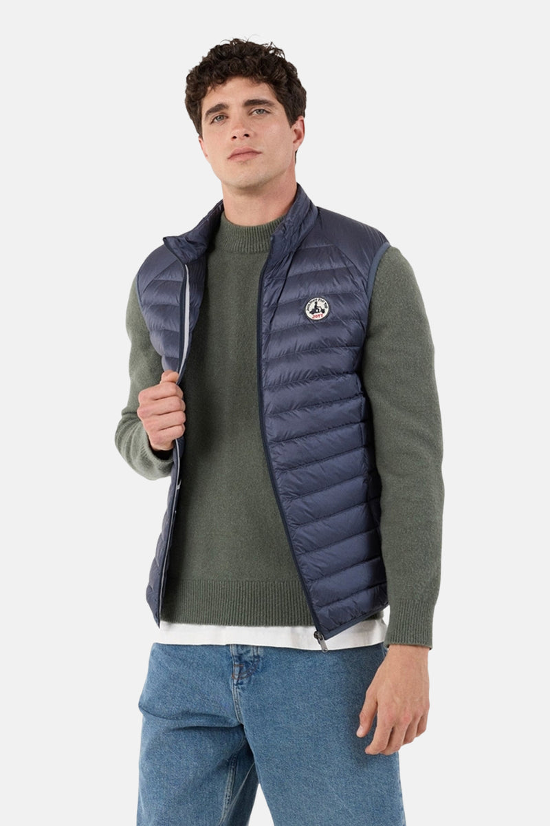 Blauw mouwloos vest van JOTT, gedragen over een groene trui met een spijkerbroek.