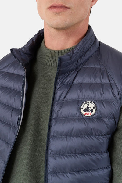 Veste sans manches bleue de JOTT, portée sur un pull en maille verte.