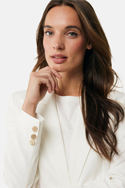 Blazer blanc de MEXX avec boutons dorés sur la manche et porté sur un T-shirt uni.