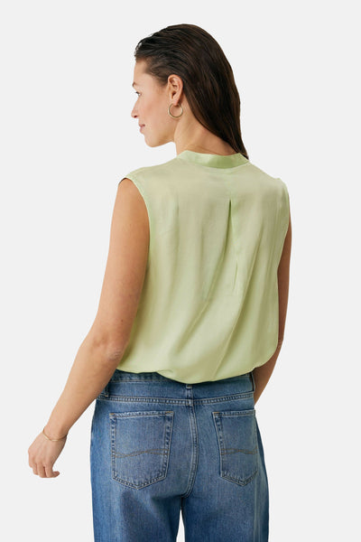 Chemisier vert sans manches de MEXX, avec un pli au dos, porté avec un jean bleu.