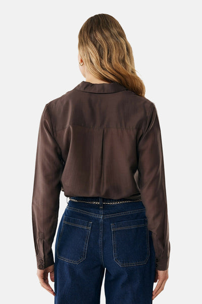 Chemise à manches longues brun, de MEXX, avec un pli creux au dos, portée avec un jean et une ceinture chaîne.