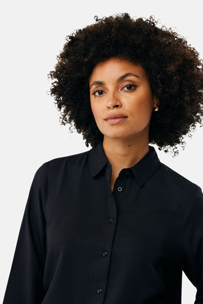 Zwarte blouse met lange mouwen van MEXX, gedragen door een model met krullend haar en gouden oorbellen.