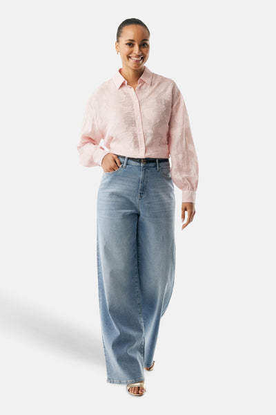 Chemisier rose à manches longues de MEXX, motif floral ton sur ton, porté avec un jean large et des sandales dorées.
