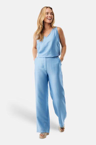 Chemisier sans manches bleu de MEXX, avec une texture subtile, porté avec un pantalon assorti et des sandales dorées.
