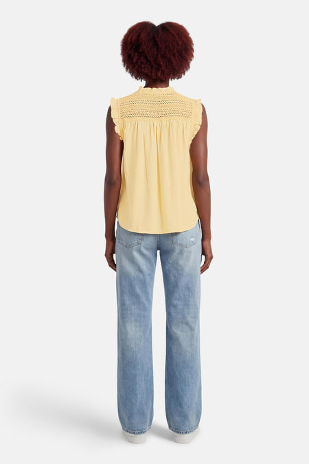 Blouse jaune sans manches de MEXX, détail en dentelle sur le haut, portée avec un jean bleu.