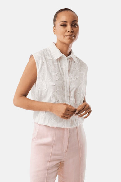 Witte MEXX blouse met kraag en reliëf geborduurde bloemenpatronen, mouwloos, gedragen door een vrouw.