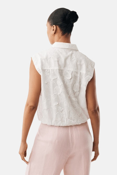Blouse sans manches blanche de MEXX avec broderie florale texturée, vue de dos portée avec un pantalon rose clair.