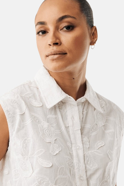 Blouse blanche de MEXX à col et motifs floraux brodés en relief, sans manches, portée par une femme.