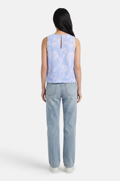 Blouse bleue sans manches de Mexx, avec motif floral blanc texturé sur rayures verticales.