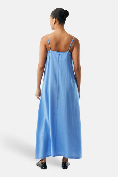 Robe longue bleue de MEXX, avec fines bretelles et coupe fluide, portée avec des ballerines à pois.
